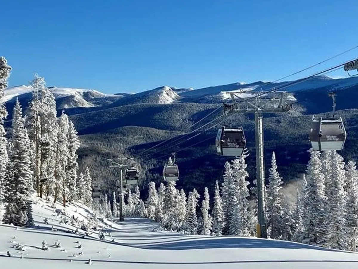 A sweeping exterior view featuring ski lift gondolas gliding above a snowy landscape, framed by snow-covered trees and a backdrop of rugged mountain peaks. The scene captures both the excitement of winter sports and the serene mountain environment.