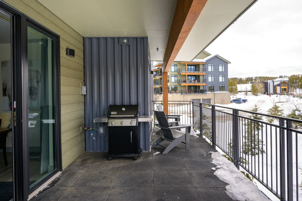 A balcony or patio scene with a barbecue grill and outdoor seating overlooking scenic mountain views. The area is ideal for relaxing, dining al fresco, or simply taking in the beauty of the natural surroundings across seasons.